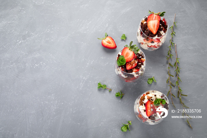 Trifles made with fresh berries and mascarpone cream on gray background. Portion desserts.
