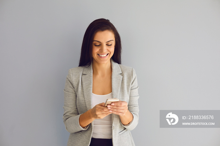 Happy elegant young businesswoman using smartphone on background