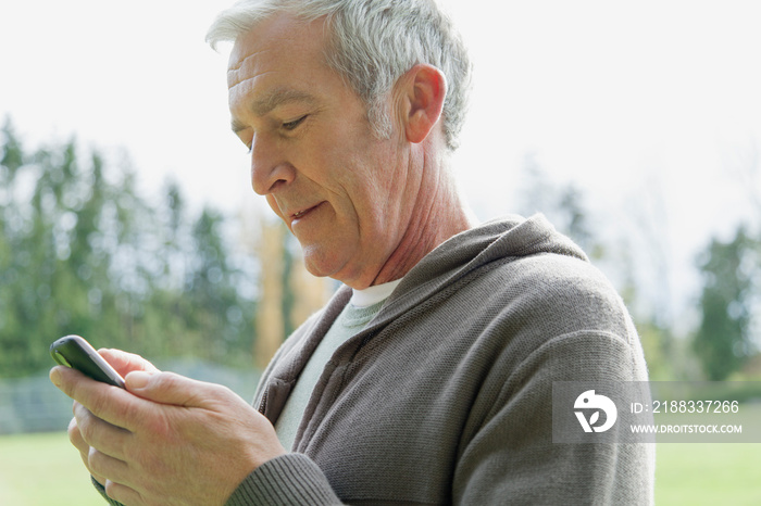 Middle-aged man texting on cell phone outdoors