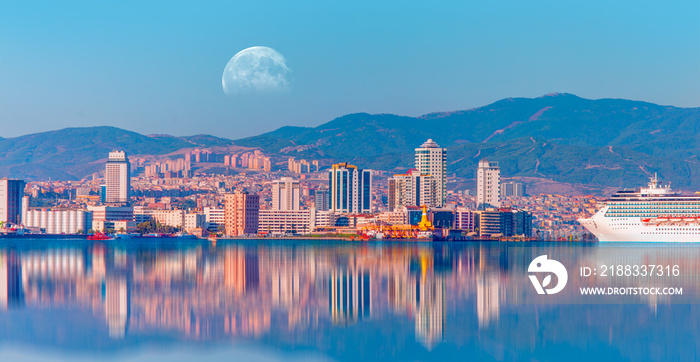 Coastal cityscape with modern buildings under blue sky with full moon - Izmir, Turkey