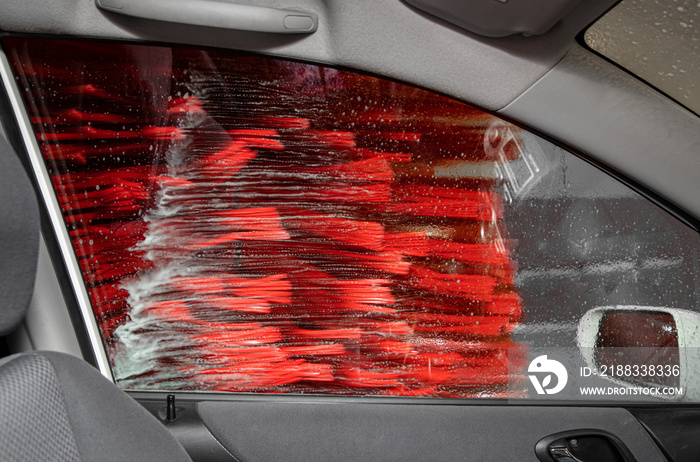 从自动洗车服务内的乘客车窗向外看，刷子在旋转和清洁