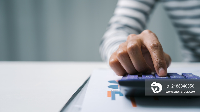 Close up business woman secretary using calculator to do math finance in office with tax accounting 