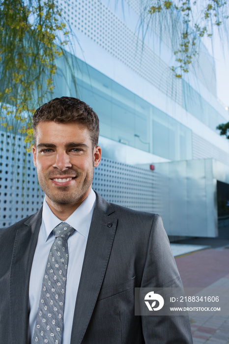 Portrait confident smiling corporate businessman outside office building