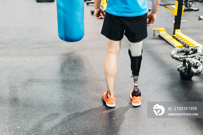 Disabled athlete with leg prosthesis training at the gym. Paralympic Sport Concept.