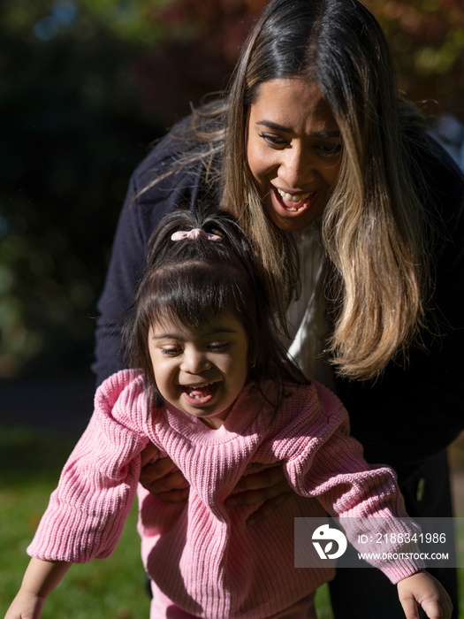 Mother and daughter with Down syndrome walking in park