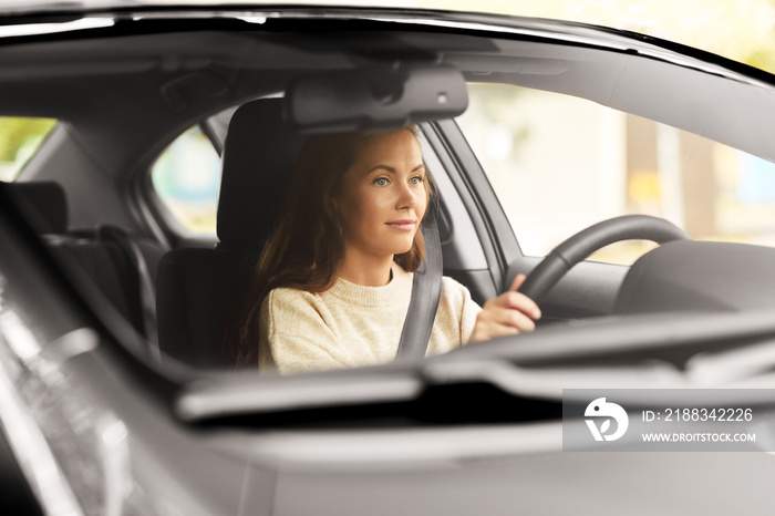 safety and people concept - young woman or female driver driving car in city