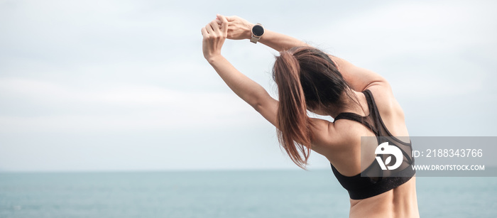 Young fitness female in sportswear stretching body against ocean view, healthy woman exercise in mor