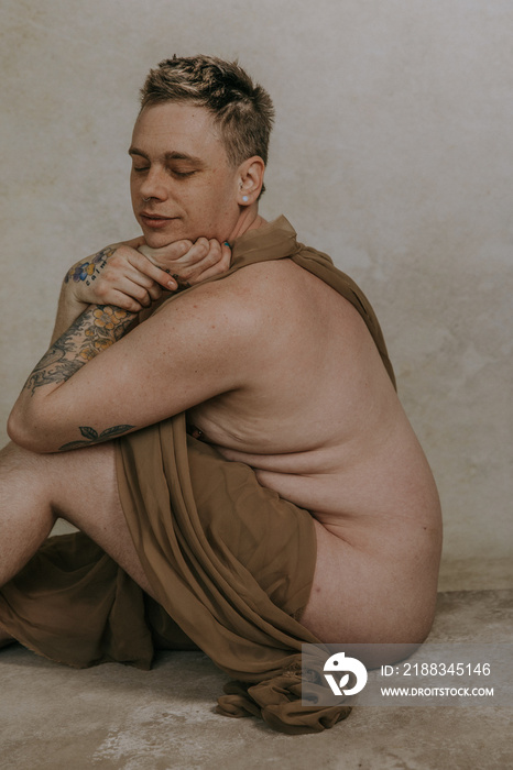 side profile of non-binary person sitting on the floor with chin in hands