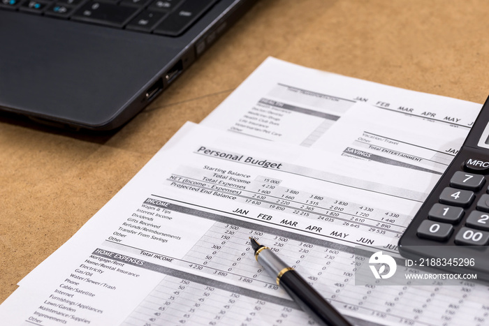 Document - Personal Budget with a laptop, a calculator and a river on the table.