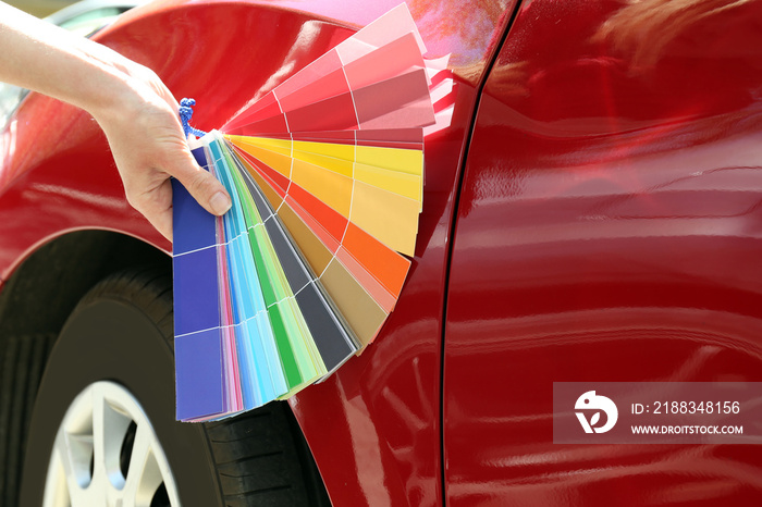 Female hand with paint samples choosing color for painting car, closeup