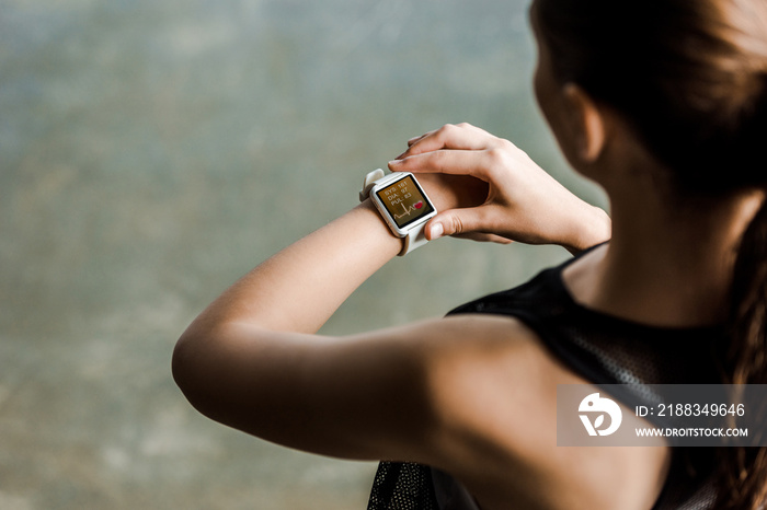 女运动员在健身房观看运动智能手表显示心率的裁剪图