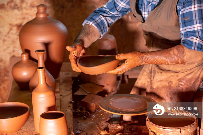 Professional potter making bowl in pottery workshop, studio.