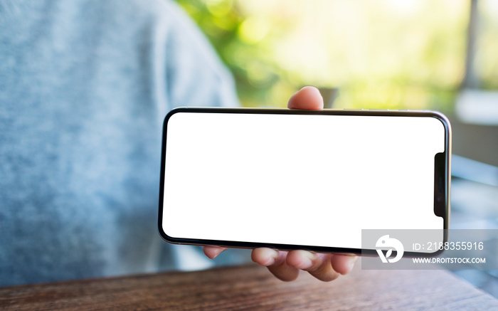 Mockup image of a hand holding and showing black mobile phone with blank desktop screen