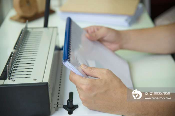 Man making report using comb binding machine - people working with stationary tools concept