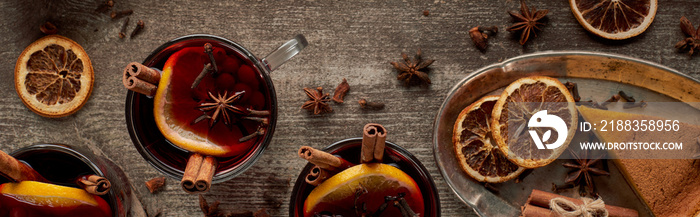 top view of red spiced mulled wine with berries, anise, orange slices and cinnamon on wooden table, 