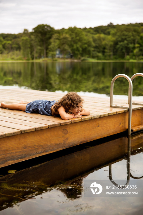 Blond girl lying on wooden jetty