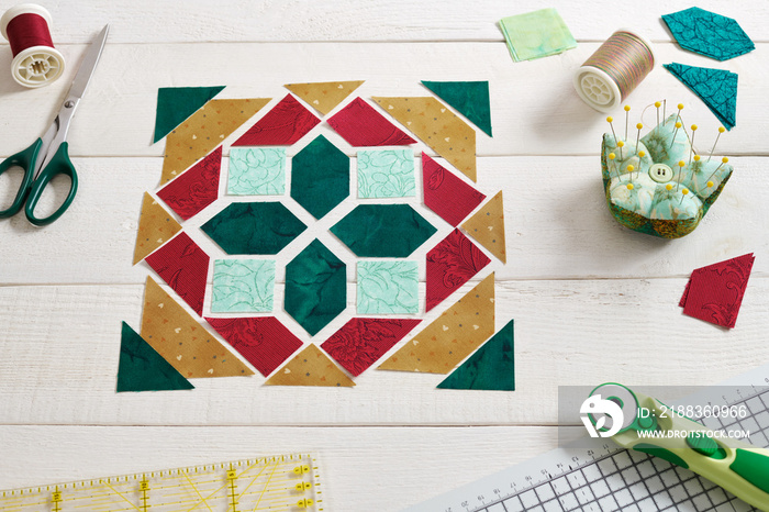 Pieces of fabric laid out in the shape of a patchwork block, sewing and quilting accessories. Tradit