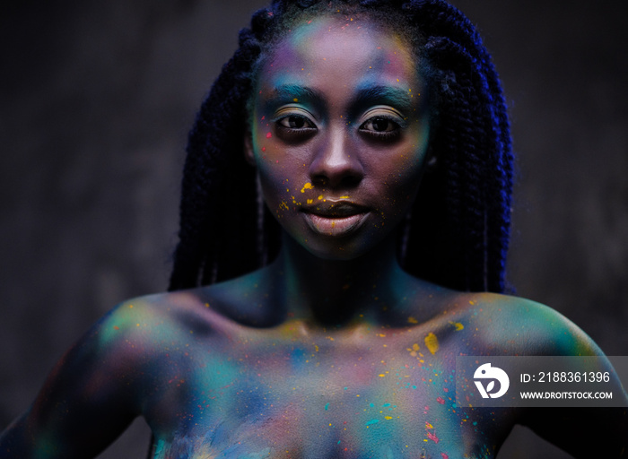 African woman with colourful powder on her face and body.