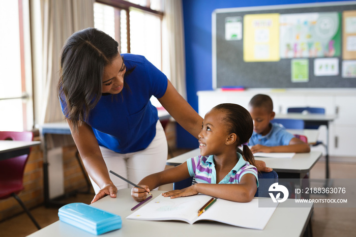 African american female teacher teaching african american girl in the class at elementary school