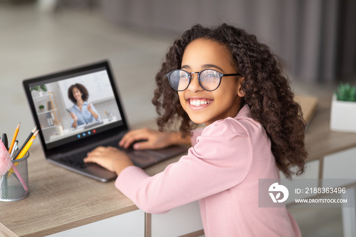 远程学习概念。微笑的黑人少女与老师在线上课