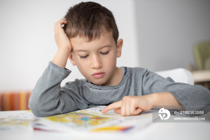 Portrait of young boy struggling with his homework at home. Children education concept