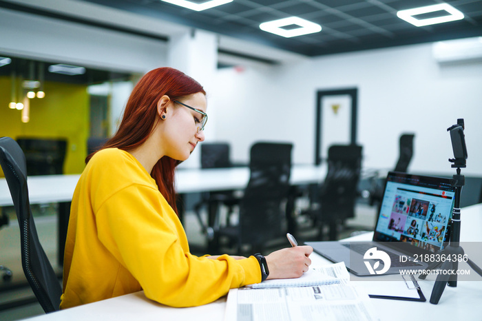 Female blogger with laptop recording video while sitting at office and talking  about startup small 