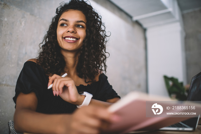 Smiling Hispanic woman working at laptop at table