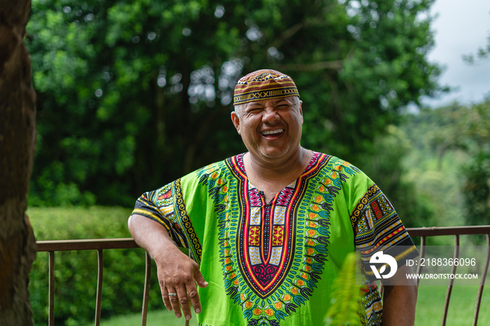 Retrato de un hombre latino muy sonriente en el exterior con una camisa muy colorida caribeña mirand