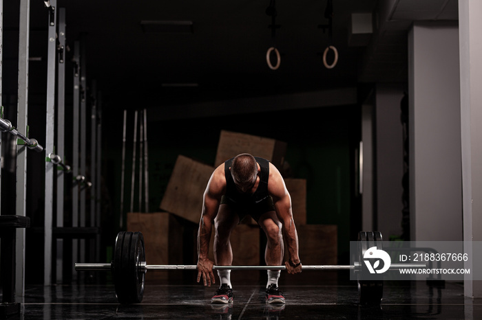 Muscular athlete lifting very heavy barbell