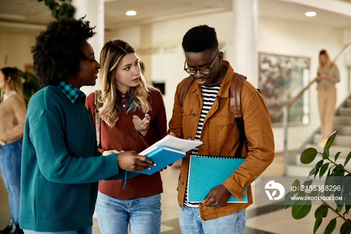 Group of college friends talk while going through lecture in hallway.