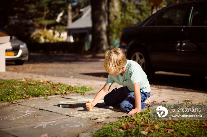 Boy (6-7) drawing on pavement