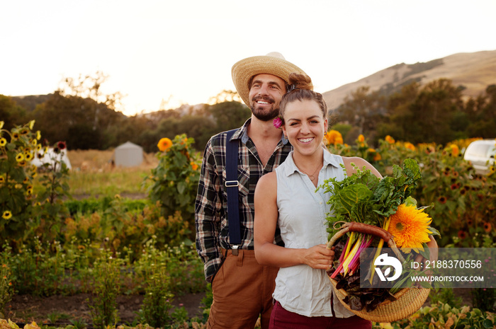 Young couple with basket of flowers and vegetables