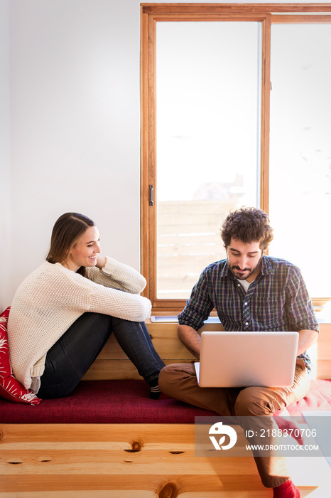 Couple sitting on bench and using laptop at home