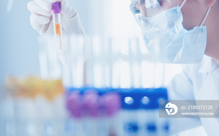 A medical or scientific researcher or doctor looking at a test tube of liquid green solution in a la