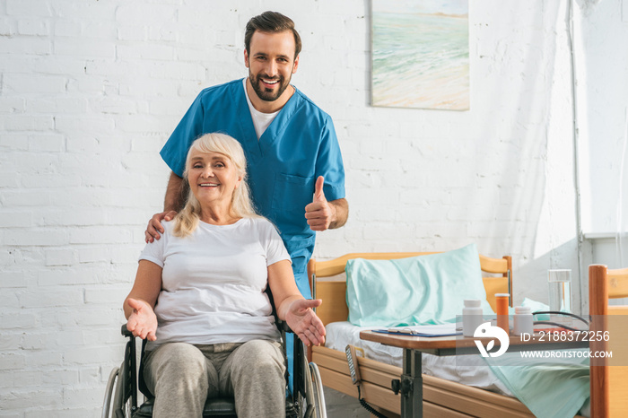 坐在轮椅上的快乐老年妇女对着镜头微笑，快乐的年轻医生竖起大拇指