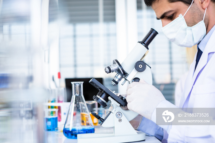 男科学家在化学实验室科学家研究中用样品试管看显微镜