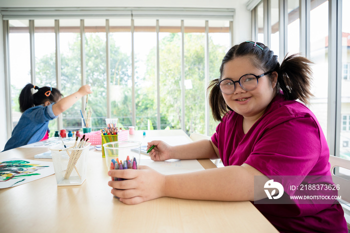 Young girls disabilities Or Downs syndrome learning about drawing shape and painting with bright sm