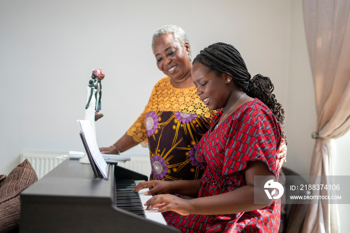 微笑的女人在家协助十几岁的孙女弹钢琴