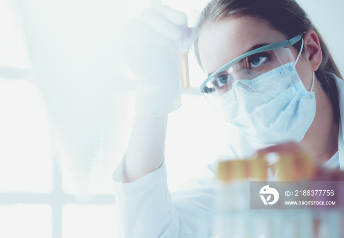 Portrait of pretty female laboratory assistant analyzing a blood sample at hospital