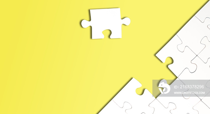 top view of jigsaw puzzle with one piece left on bright yellow background, completing a task or solv