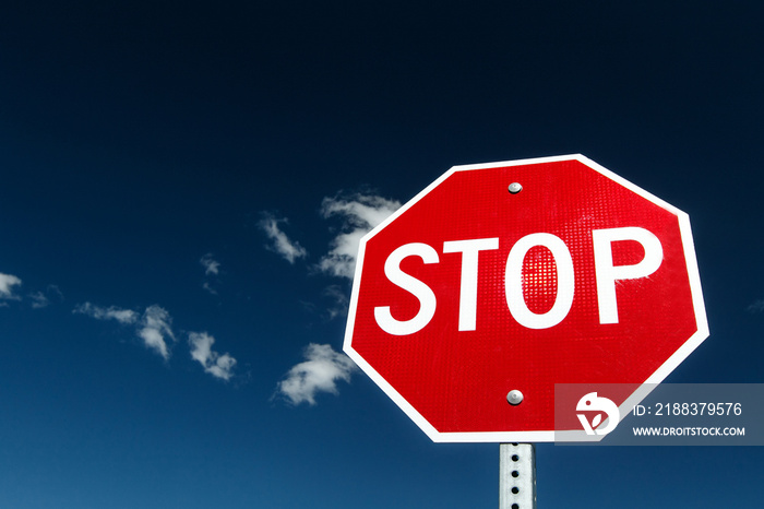 Stop sign against bright blue sky.