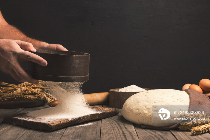 Baker sifts through the flour on a wooden table