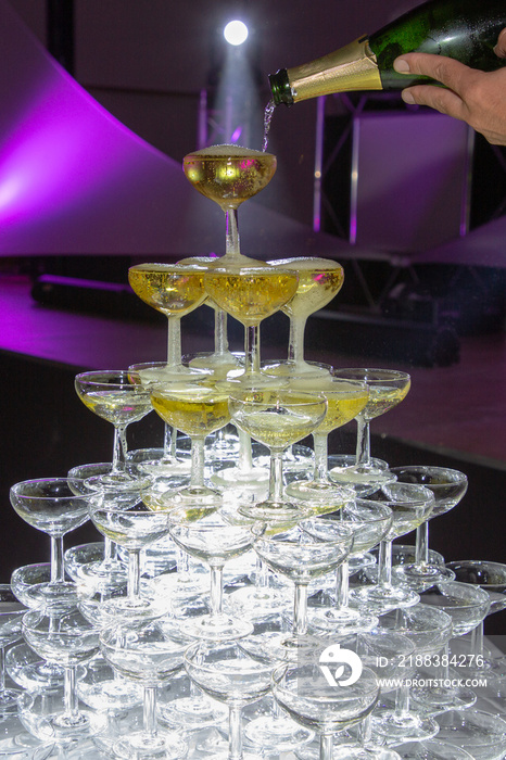 新郎在婚礼派对上用香槟级联展示玻璃金字塔