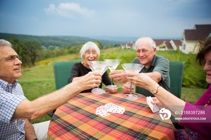 Senior people playing cards and drinking martini outside