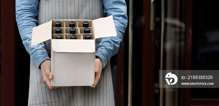 Beer for party at weekend. Bartender holds open cardboard box with bottles