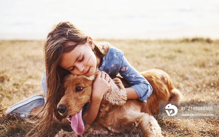 Resting near the lake. Cute little girl have a walk with her dog outdoors at sunny day