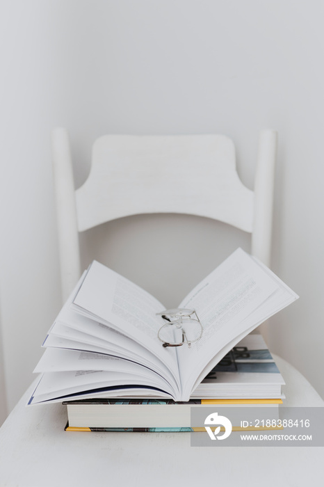 Open textbook and a pair of glasses on a white chair