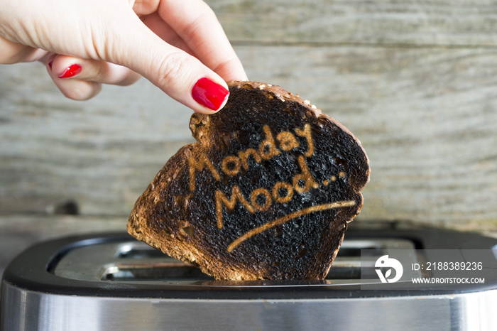 Monday mood concept with slice of burned toast bread in woman hand