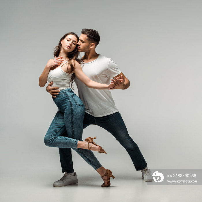 dancers in denim jeans dancing bachata on grey background