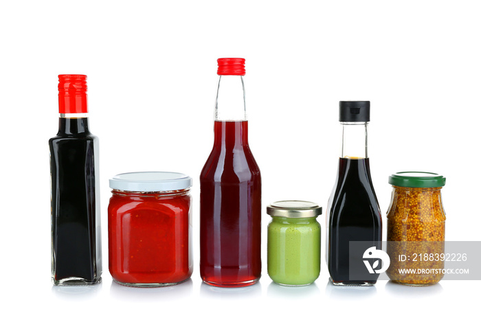 Glass jars and bottles of different sauces isolated on white